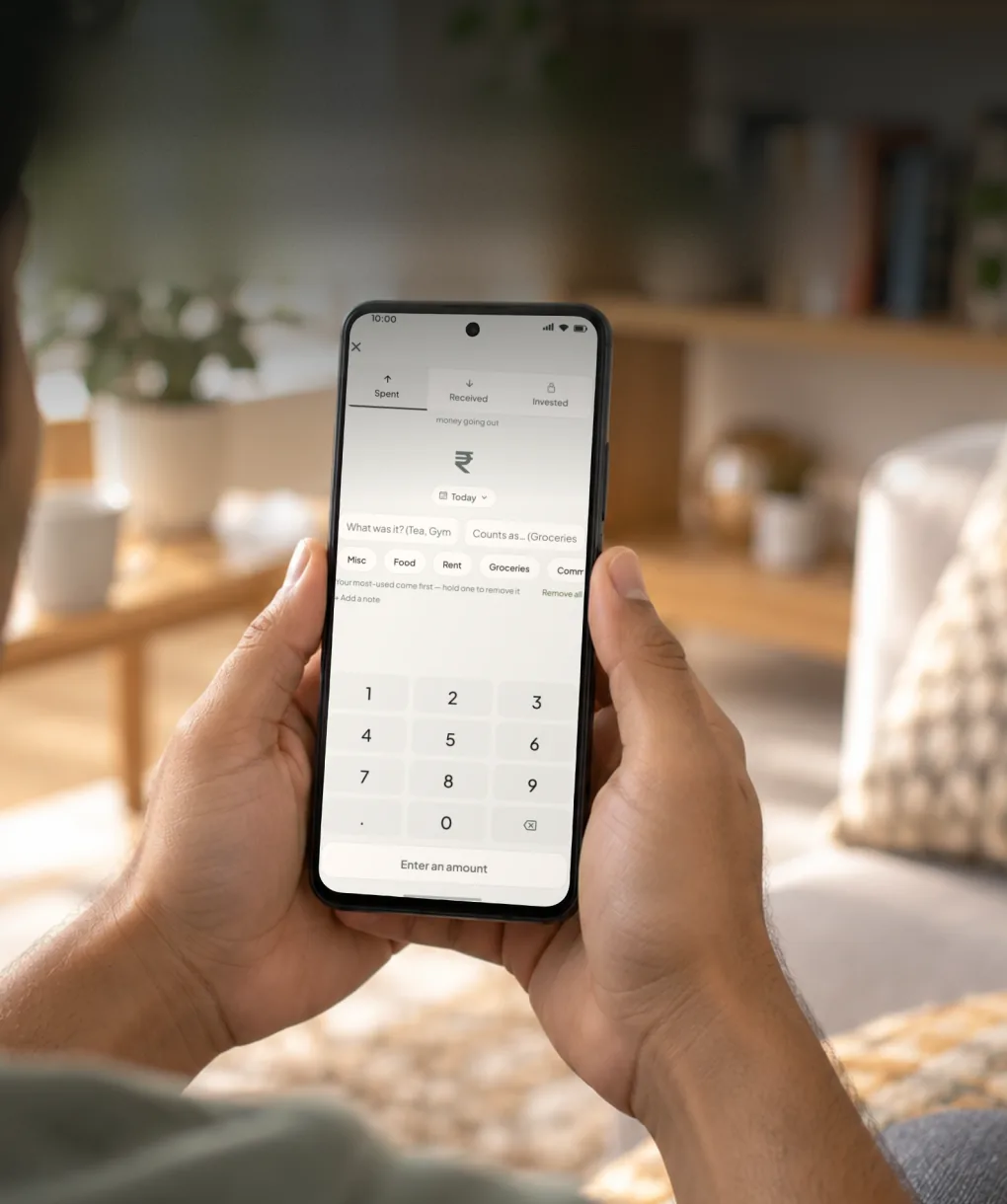 Hands holding a phone open on Mickle's add-entry screen, with Spent, Received and Invested tabs and a number pad